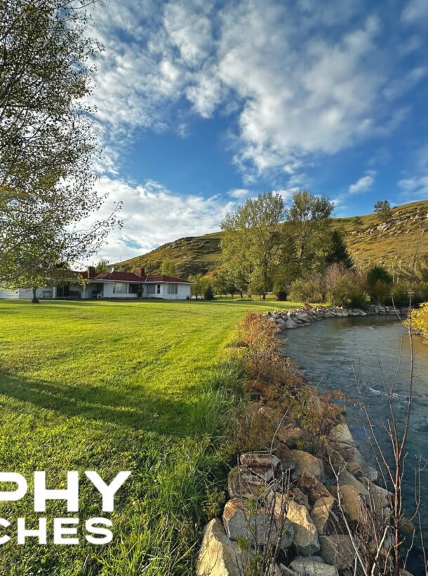 Trophy Ranches, trees, a river, and the exterior of a house with a hill in the background